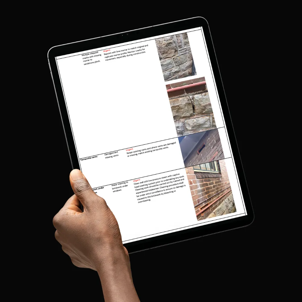 Hand holding a tablet displaying a condition report with photos of damaged masonry and brickwork and text describing urgent repairs.