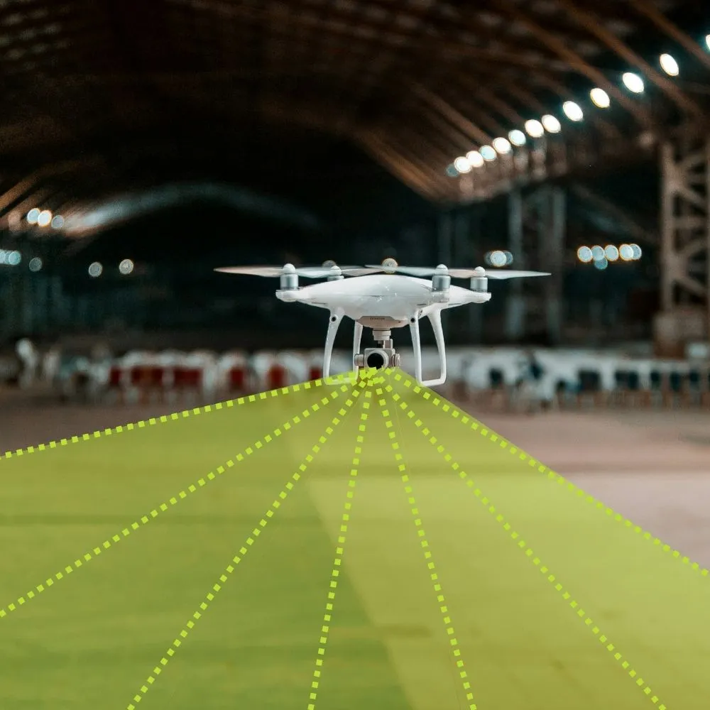 White drone hovering indoors with yellow digital lines indicating camera sensor coverage.