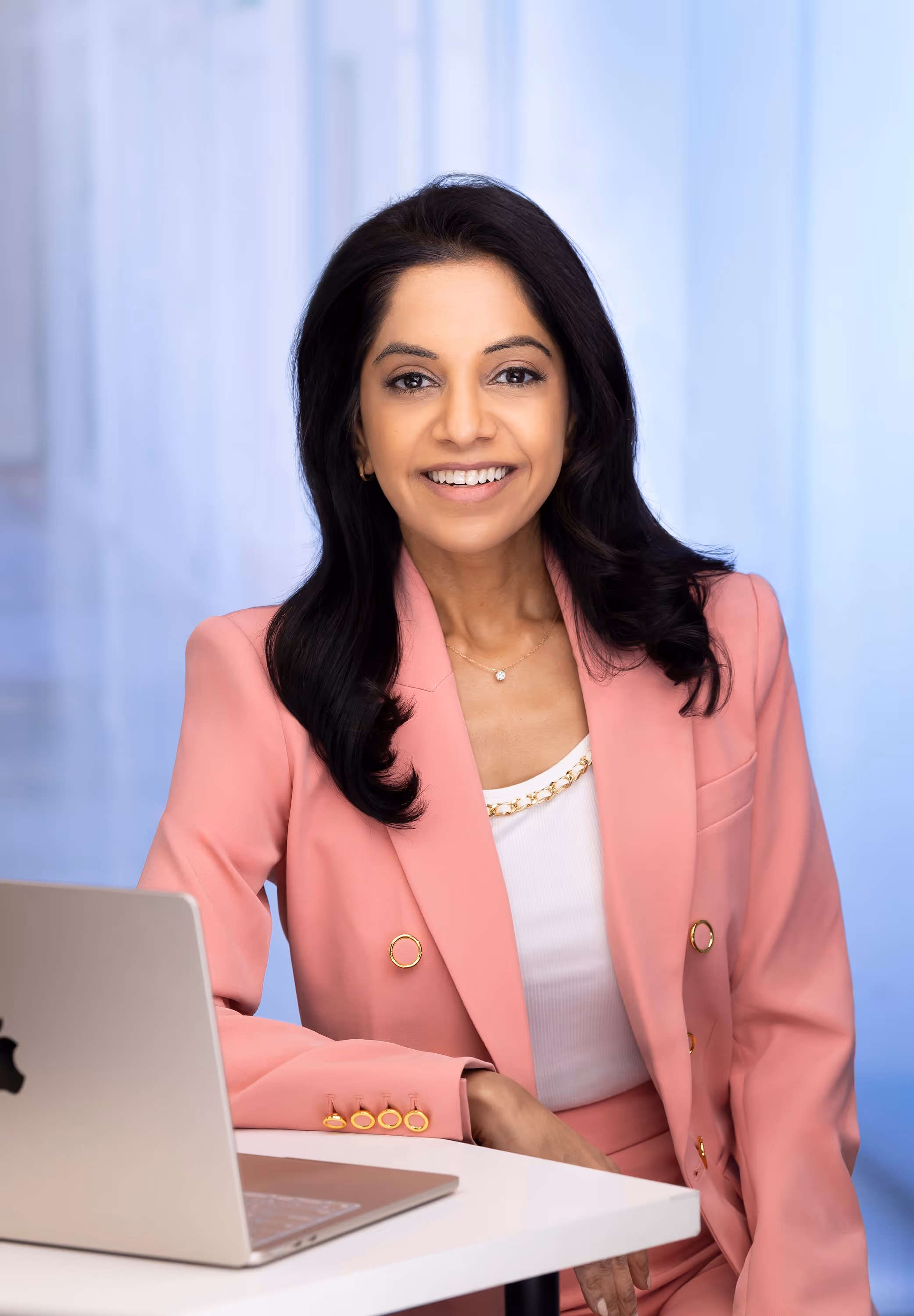 Dr. Shah smiling in front of a laptop