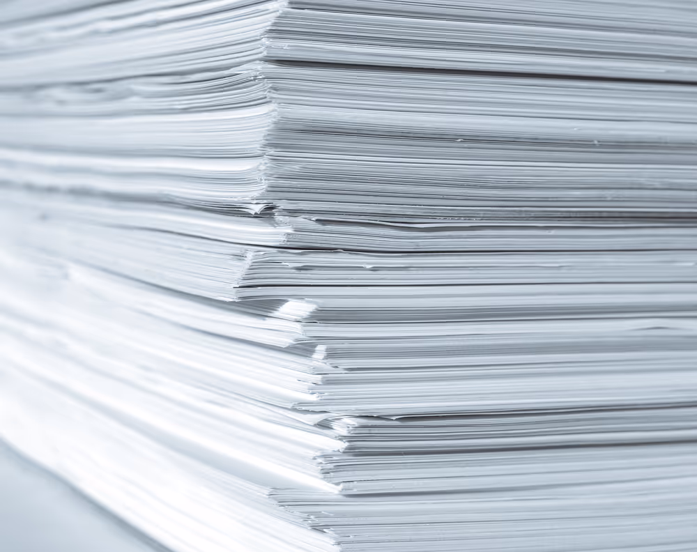 Ein großer Stapel ungebundener weißer Papiere von der Seite aufgenommen.