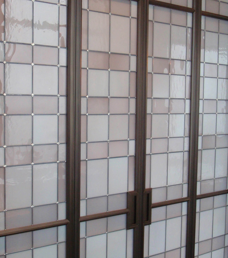 CNR Group NYC luxury home builder project interior: Close-up of brown-framed glass doors with frosted square and rectangular panes.