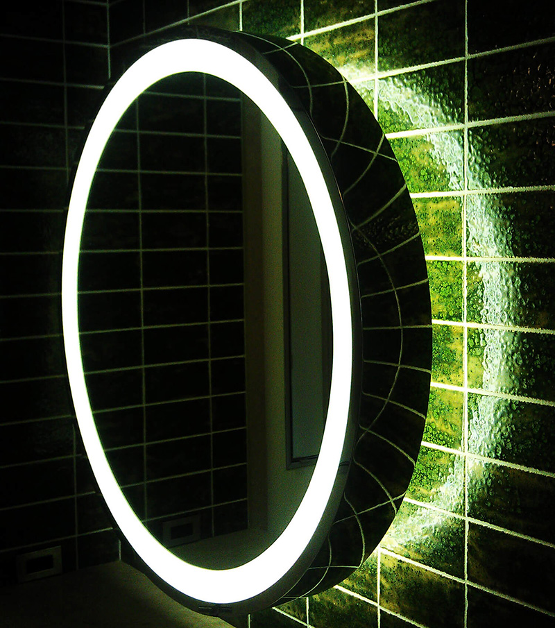 CNR Group NYC luxury home builder project: Illuminated round mirror with a glowing white LED ring mounted on a dark green tiled wall.
