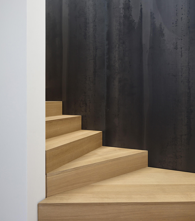Modern custom millwork wood staircase with wide steps and a dark textured wall backdrop.