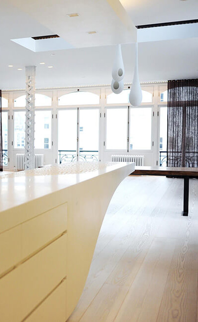 CNR Group NYC luxury home builder: Bright modern interior with light wood flooring, large windows, white cabinets, and unique hanging white pendant lights.