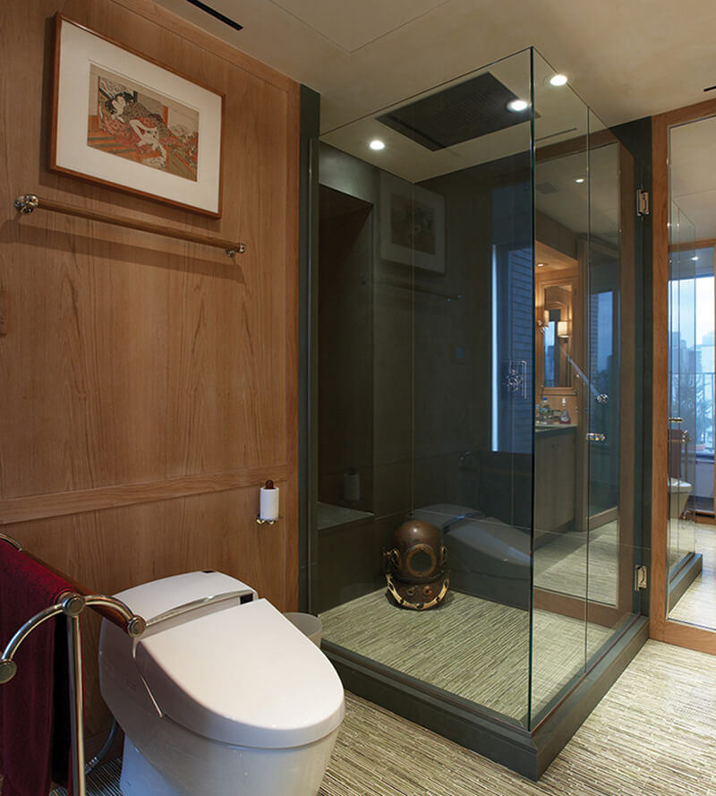 CNR Group luxury home construction interior: Modern bathroom with wooden walls, a white toilet, glass-enclosed shower, and a vintage diving helmet inside the shower.