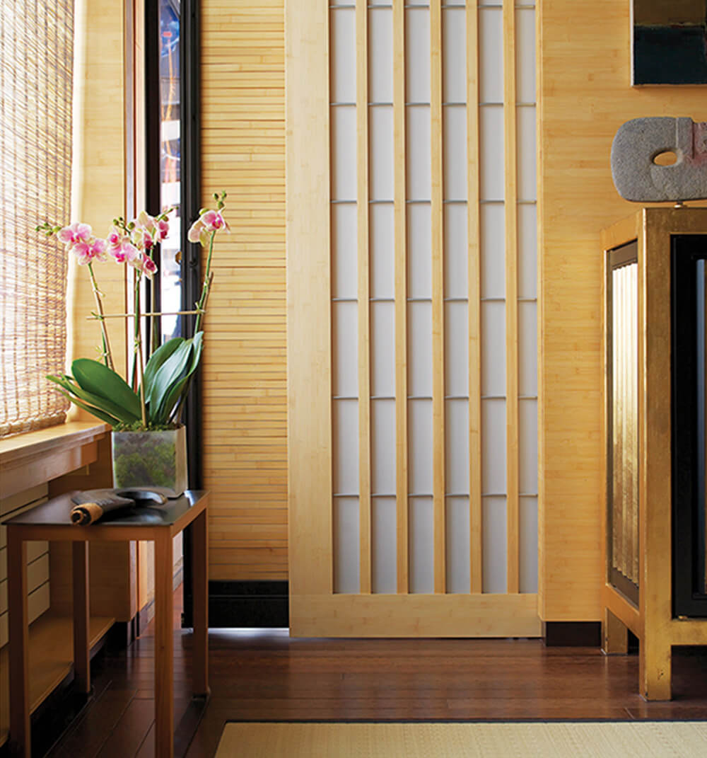 CNR Group luxury home project management interior: Minimalist interior with a small table holding an orchid plant near a shoji-style sliding door and bamboo window shades.