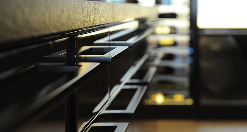 Close-up of CNR Group custom metalwork modern black kitchen cabinet handles with a reflective surface.