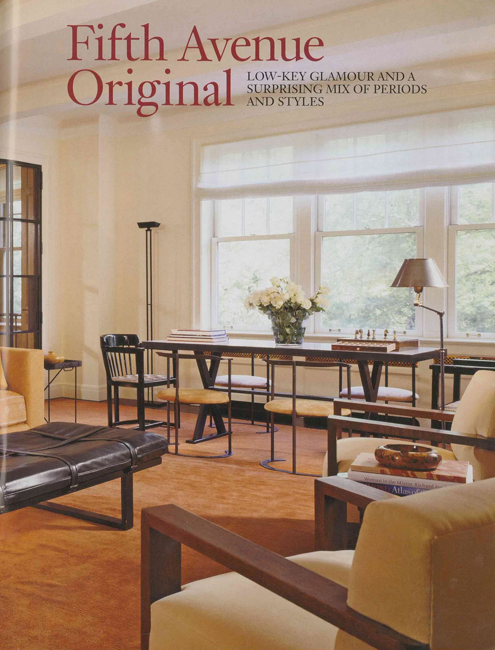 CNR Group luxury home builders project interior: a bright room with large windows, featuring a long table with chairs, a vase of white flowers, a chess set, and comfortable seating on an orange carpet.