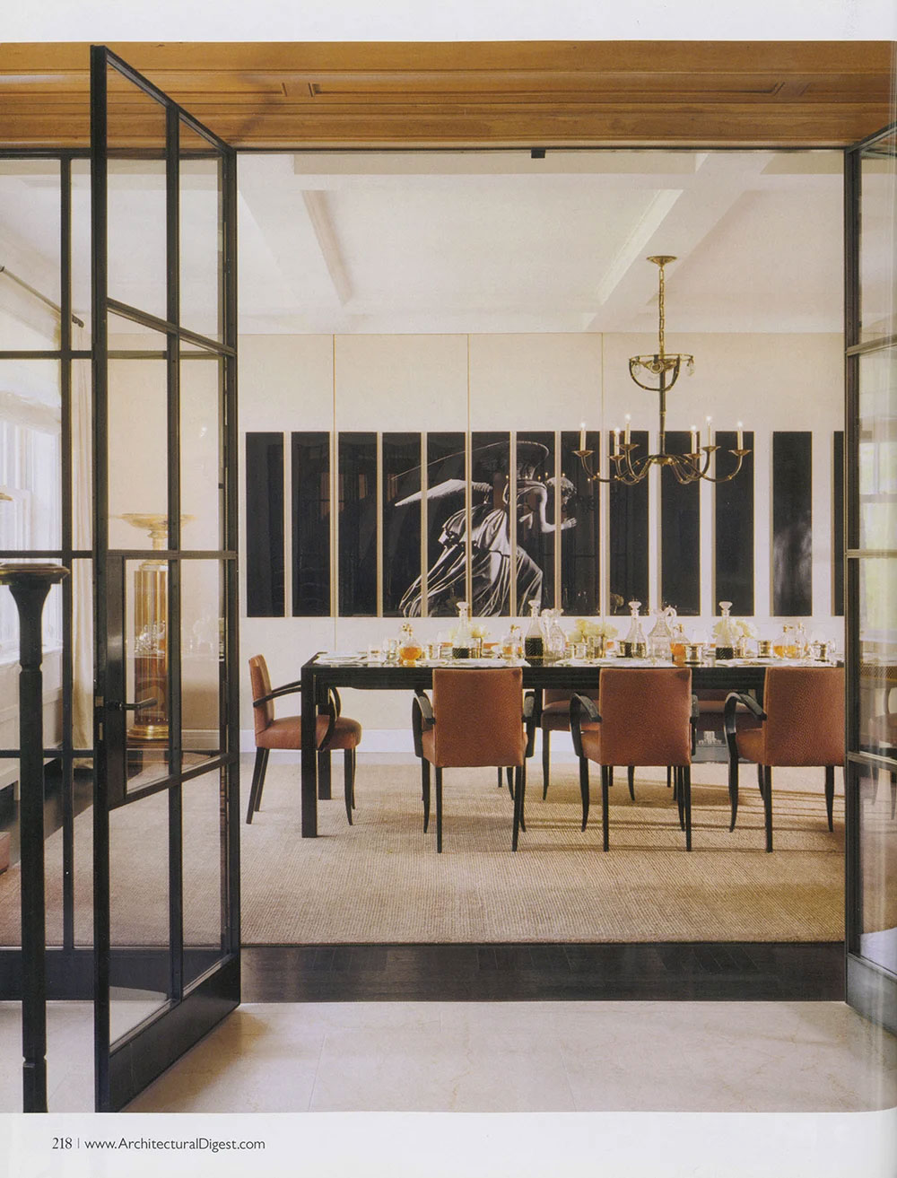 CNR Group luxury home builders project interior: Modern dining room with a black table, six brown leather chairs, a large artwork of a winged figure, and a gold chandelier.
