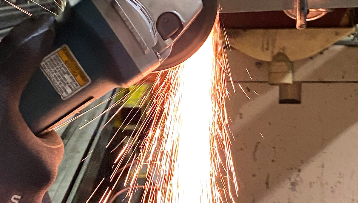 Close-up of a handheld angle grinder producing bright sparks while cutting or grinding metal for CNR Group custom metalwork.