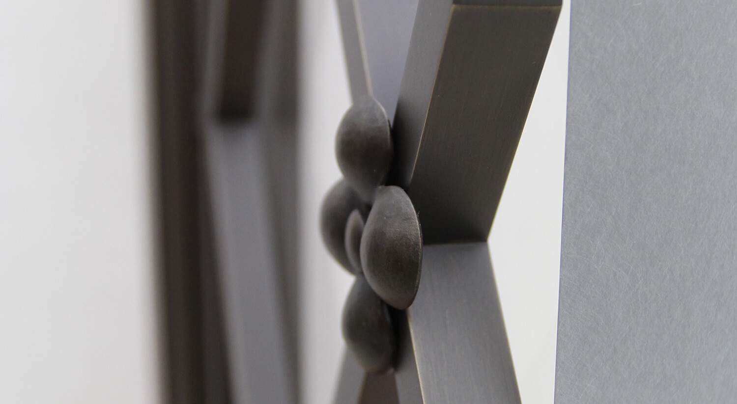Close-up of CNR Group custom metalwork: decorative metal joining with rounded rivets on an X-shaped metal structure.