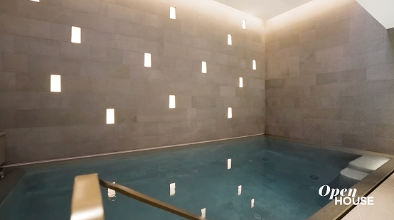 An indoor pool with blue water and wall featuring multiple rectangular lights created by luxury home builder CNR Group.