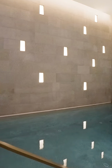 Tiny squares of window light land on a beige interior stairway wall in a CNR Group NYC luxury home.