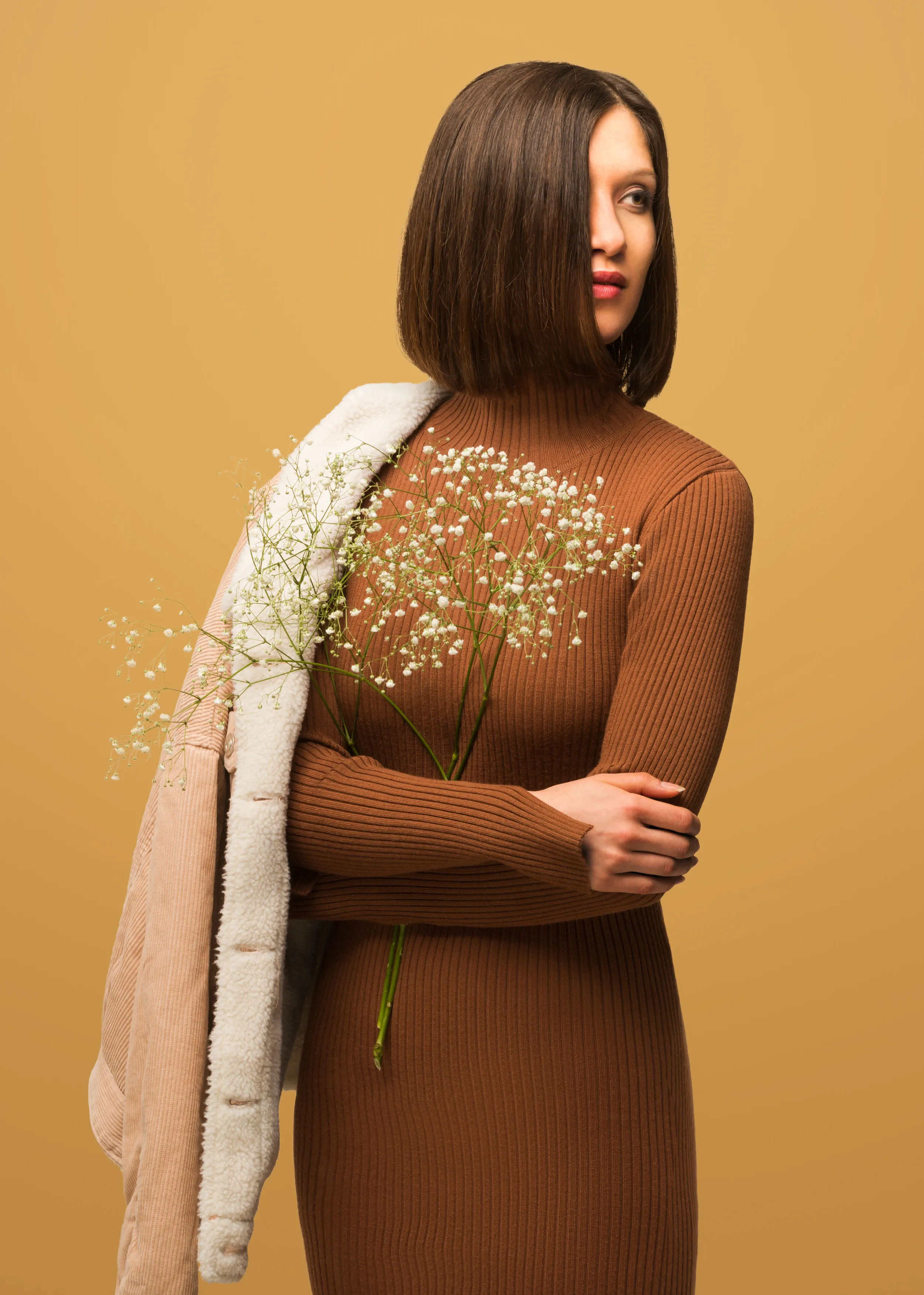 Frau mit geradem Bob und braunem Kleid vor beigem Hintergrund – stilvolles Motiv von Zom Gwafför.