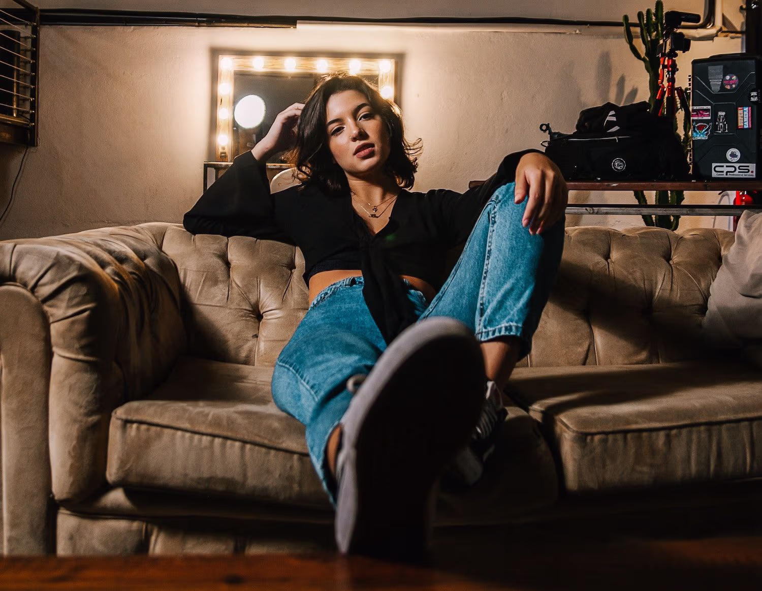 Frau in Jeans und schwarzem Top sitzt auf einer Ledercouch