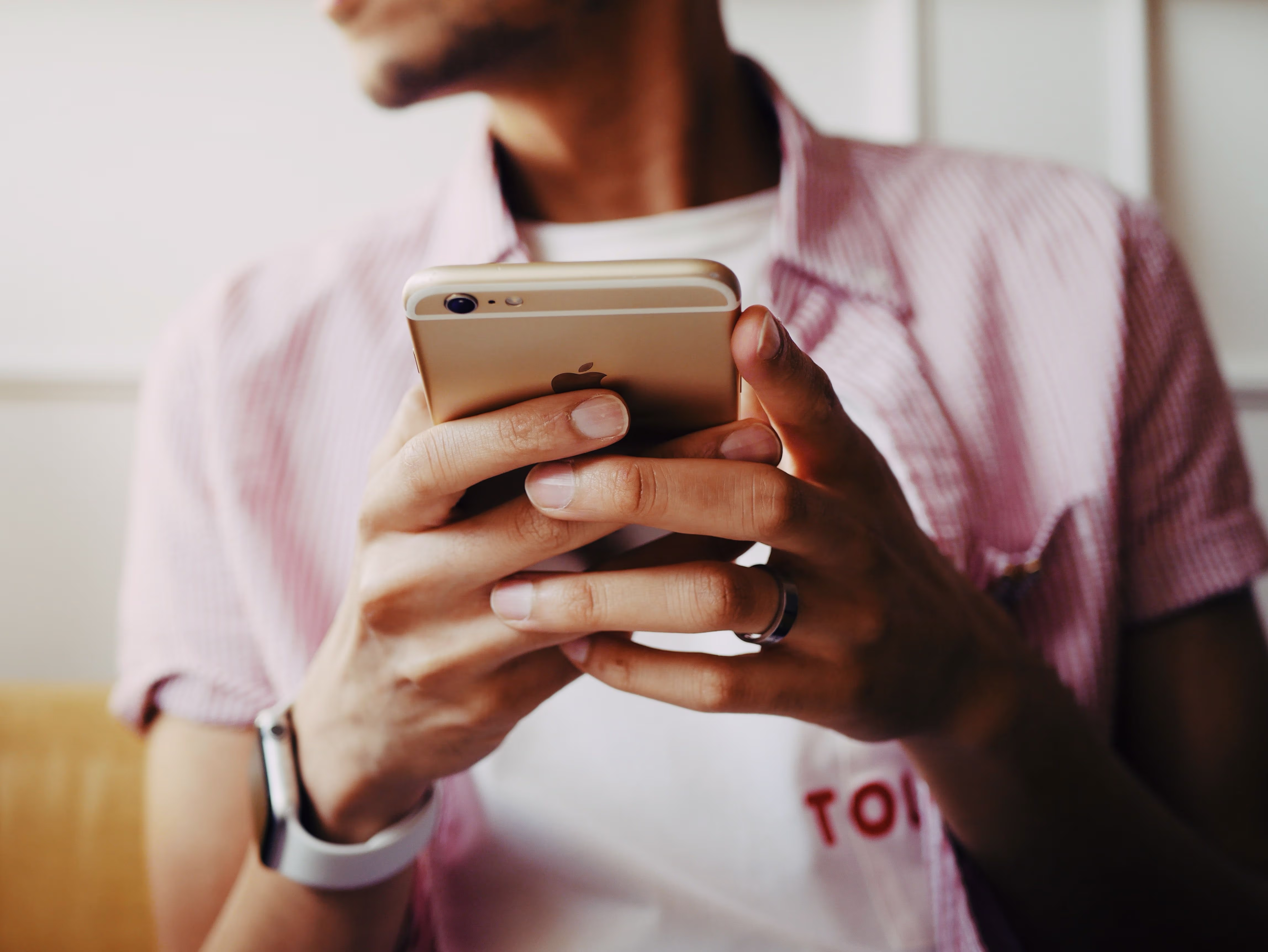 Mann in rosa Hemd hält Smartphone
