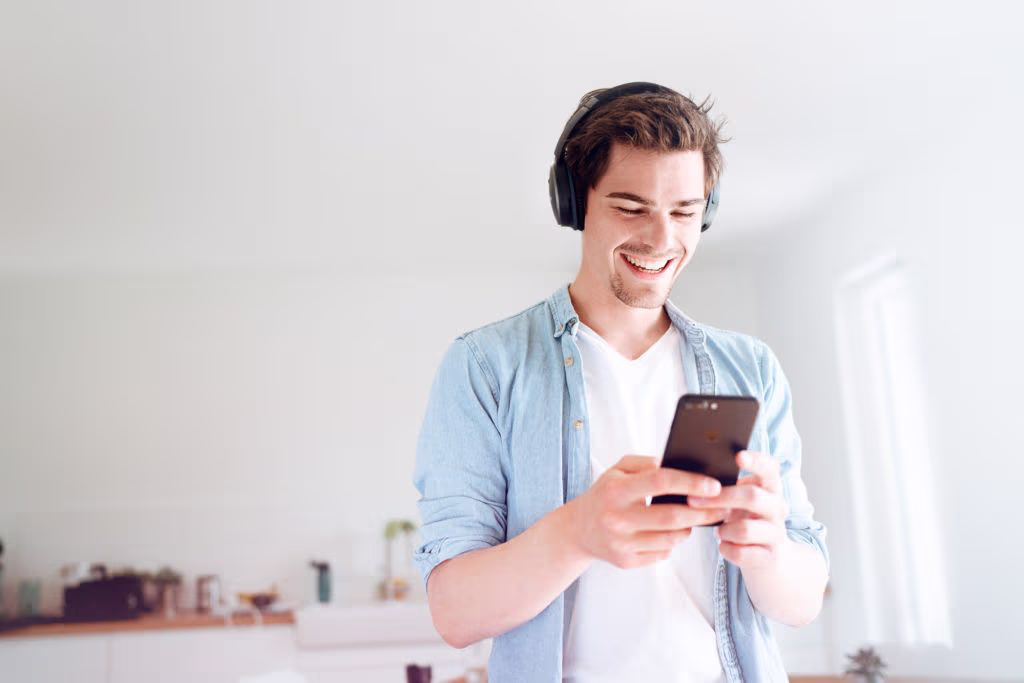 Mann mit Kopfhörern schaut auf sein Handy