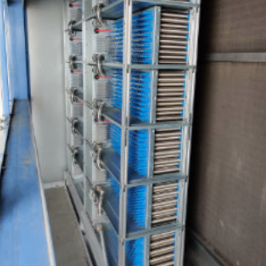 Close-up side view of a large industrial air handling unit with metal frames, blue fins, and numerous cylindrical components.