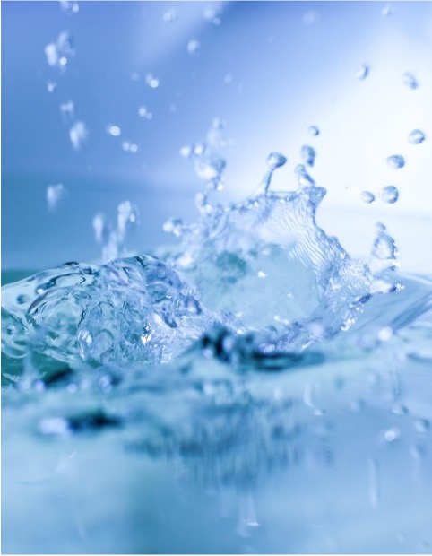 Close-up of water splashing with droplets suspended in the air against a blue background.