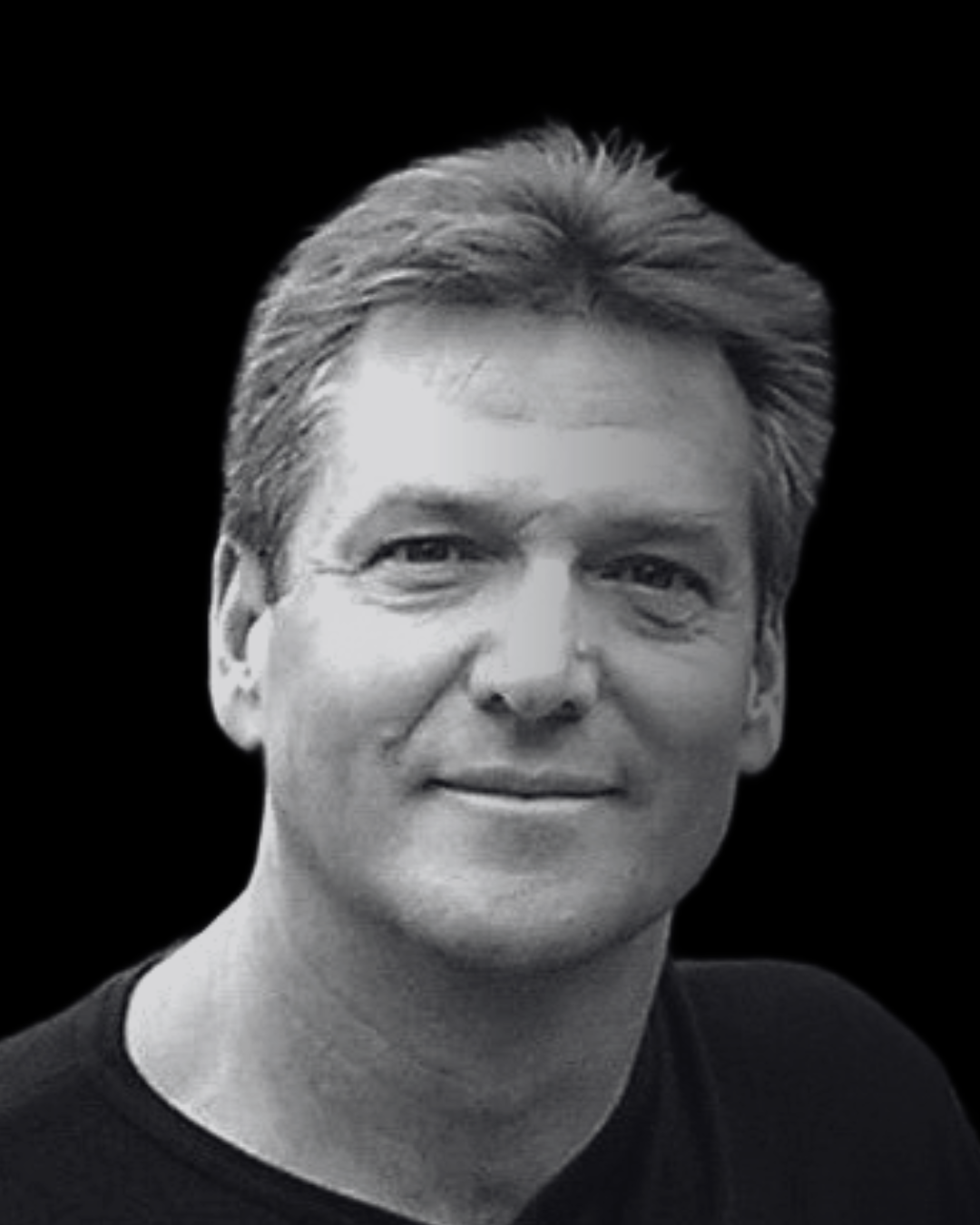 Black and white close-up portrait of a middle-aged man with short hair wearing a dark shirt against a black background.