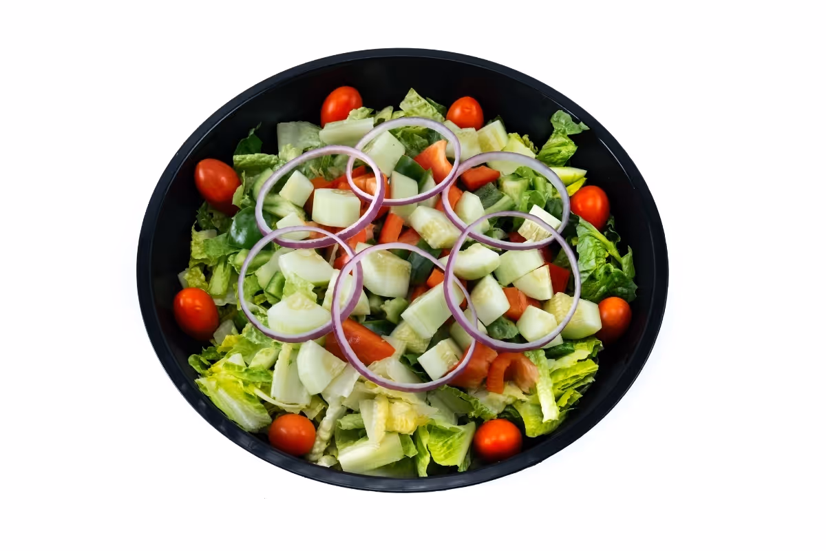 Black bowl filled with fresh garden salad including lettuce, cherry tomatoes, cucumber, red bell pepper, and sliced red onions.
