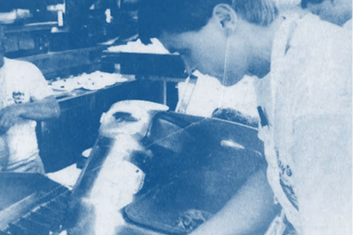 Two people in a kitchen preparing food, one person focused on a tray of pastries.