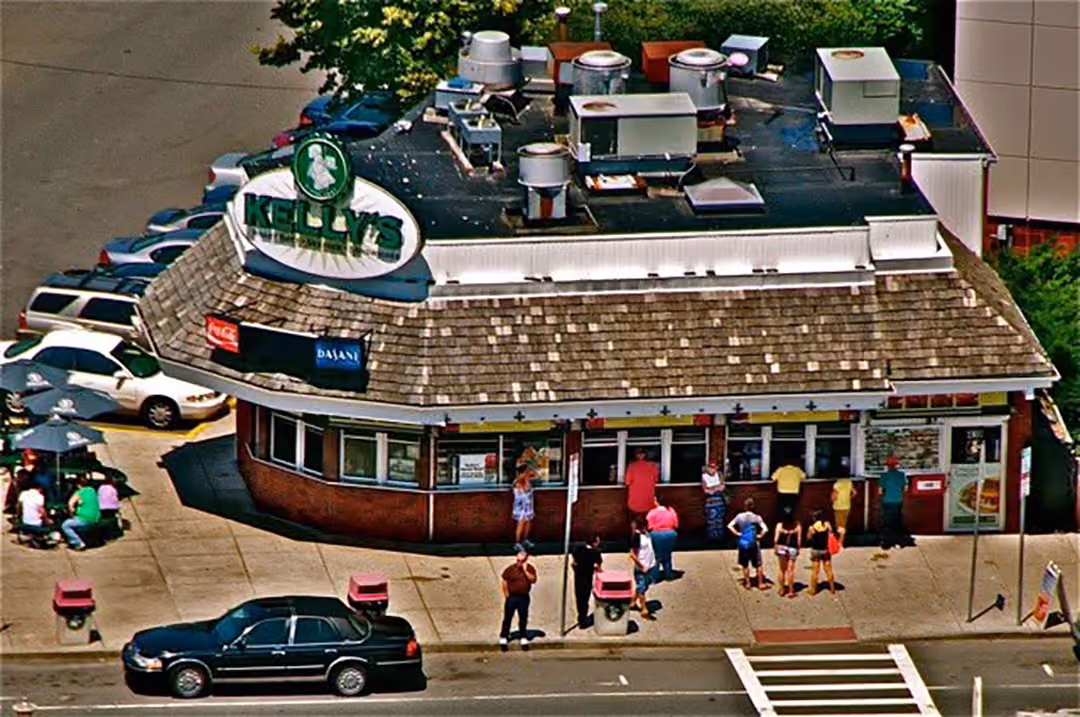 Kelly's restaurant with customers lined up at order windows on a sunny day.
