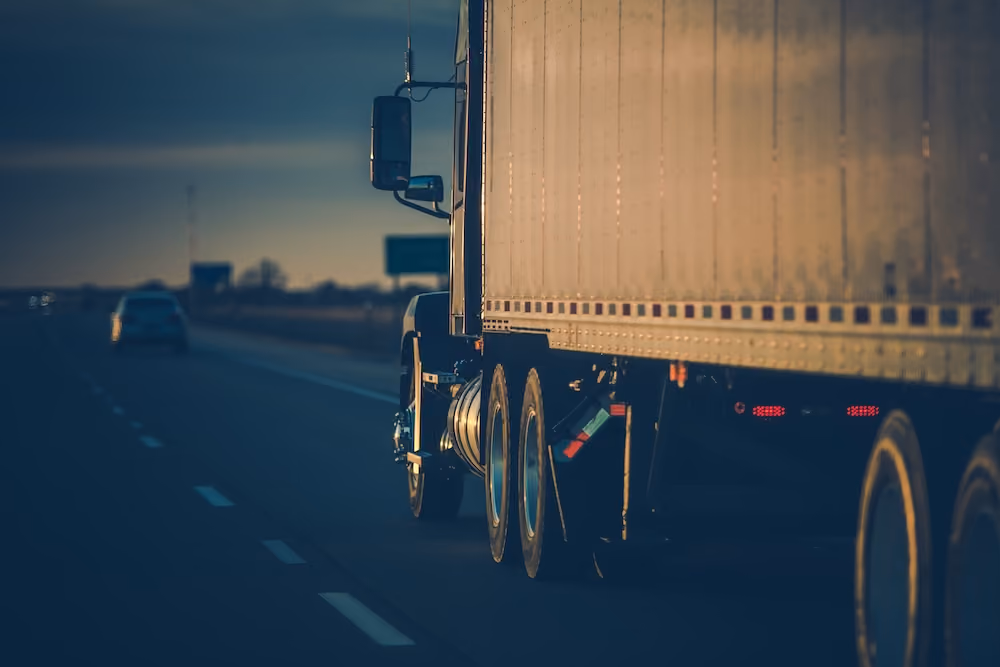 Close-up of commercial freight truck hauling cargo at dusk on multi-lane highway