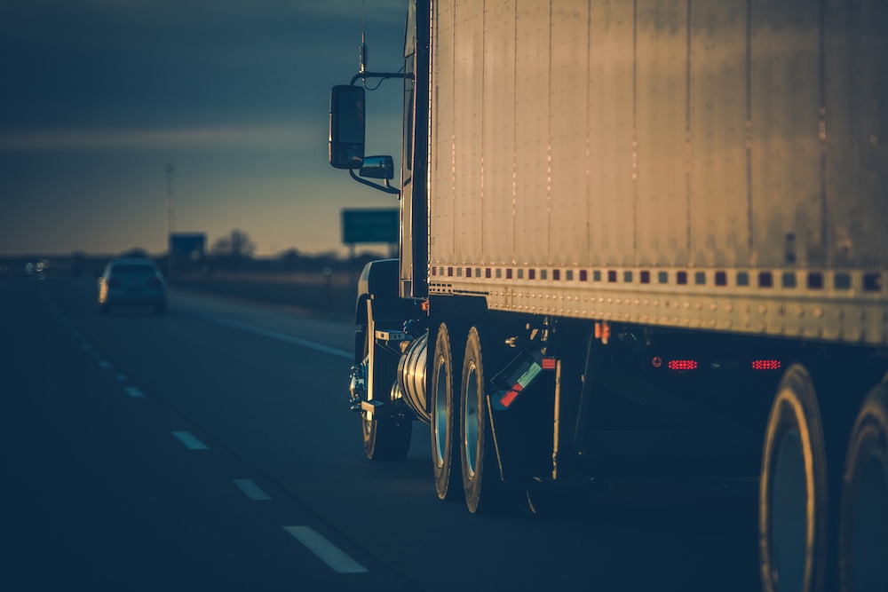 Close-up of commercial freight truck hauling cargo at dusk on multi-lane highway
