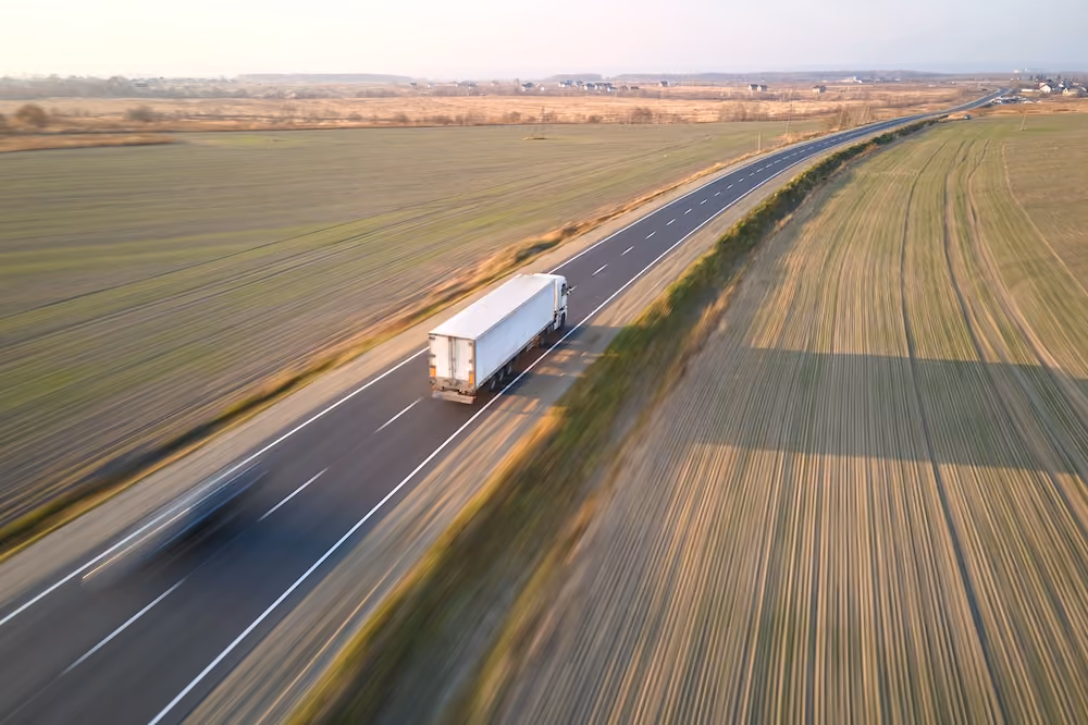 White semi-truck driving on a rural highway transporting freight across long distance