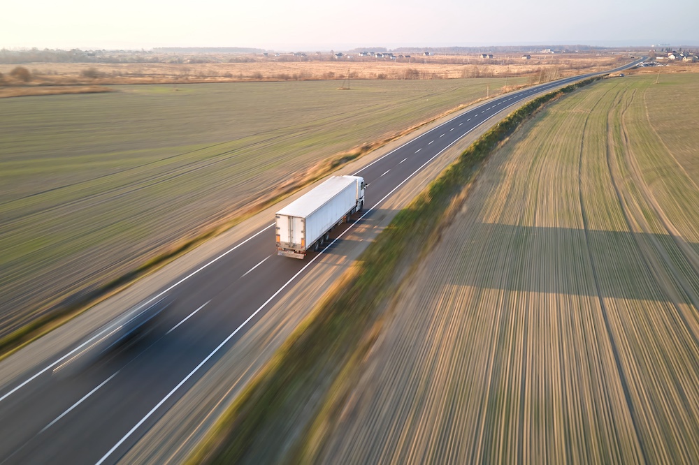 White semi-truck driving on a rural highway transporting freight across long distance
