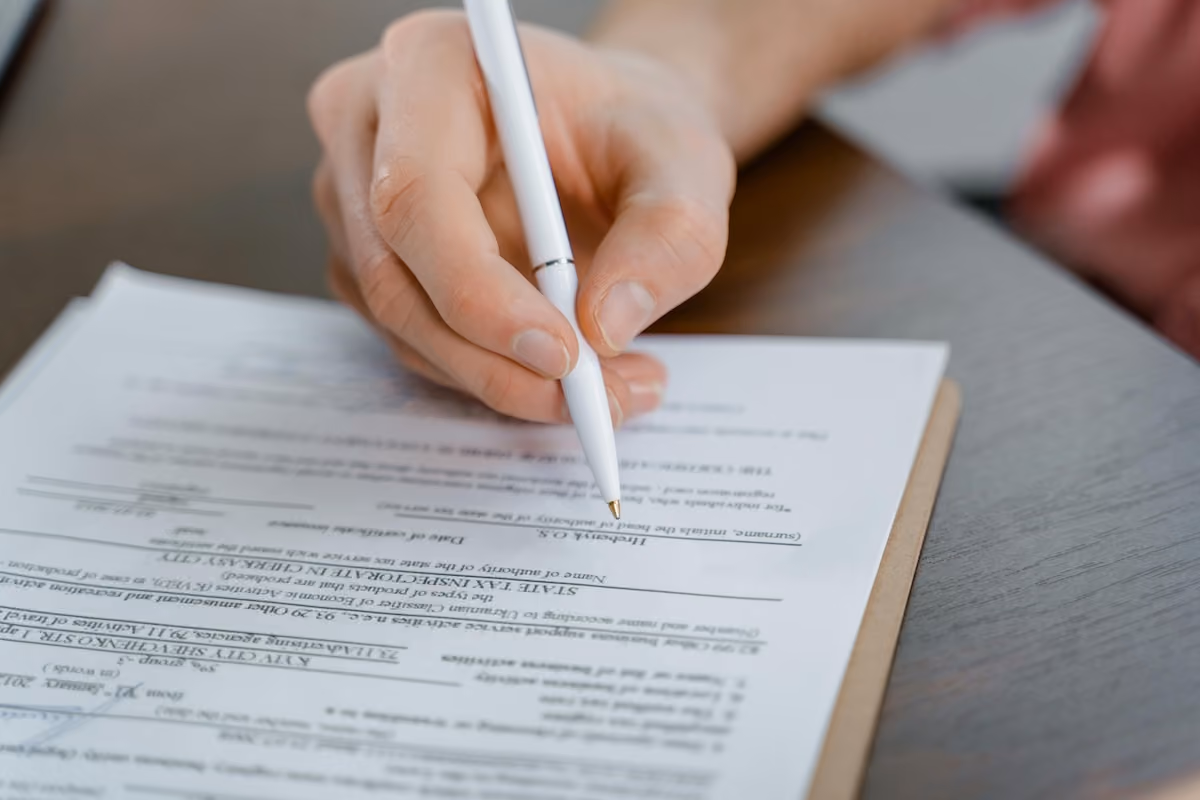 hand holding a pen and filing out their taxes