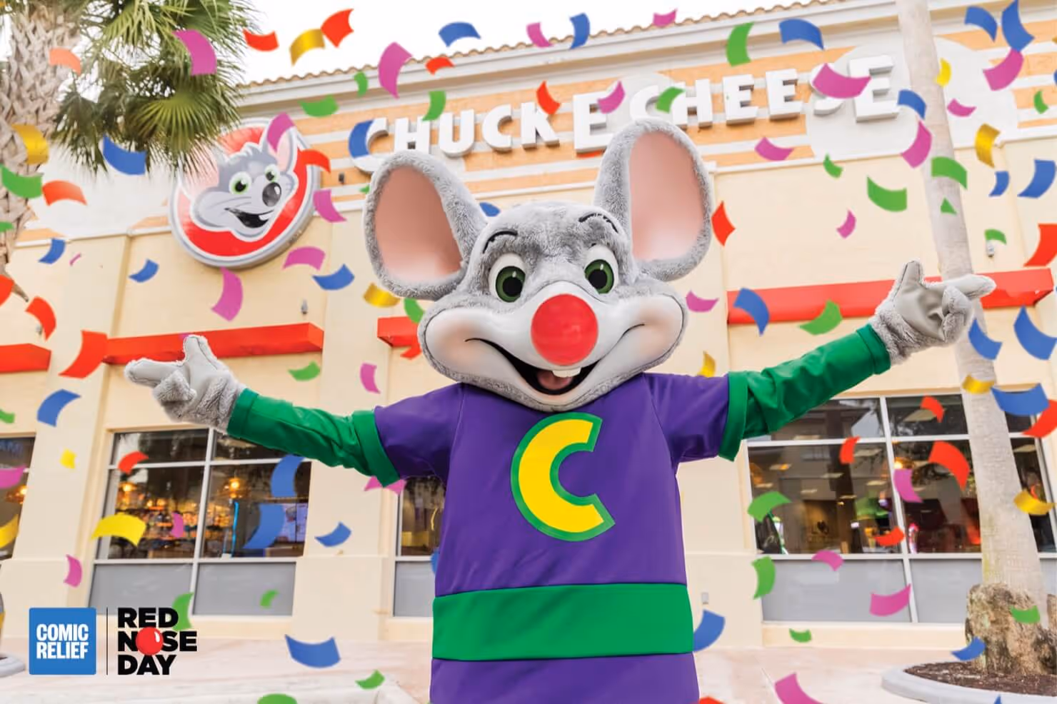Chuck E. Cheese himself sporting a red nose in front of a Chuck E. Cheese with lots of confetti