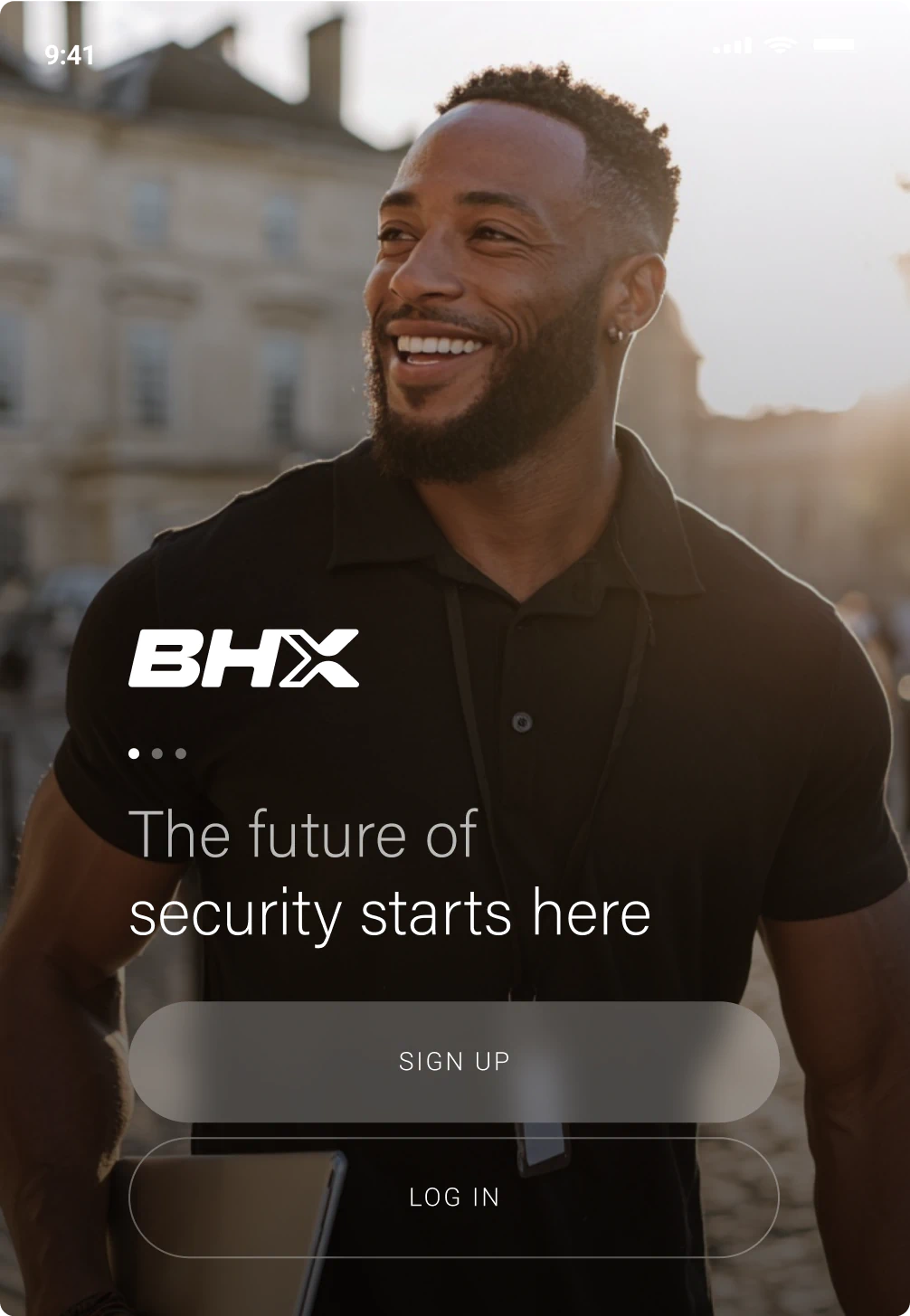 Smiling man wearing a black polo shirt with a security badge, standing outdoors in soft sunlight with text overlay about security and sign-up options.
