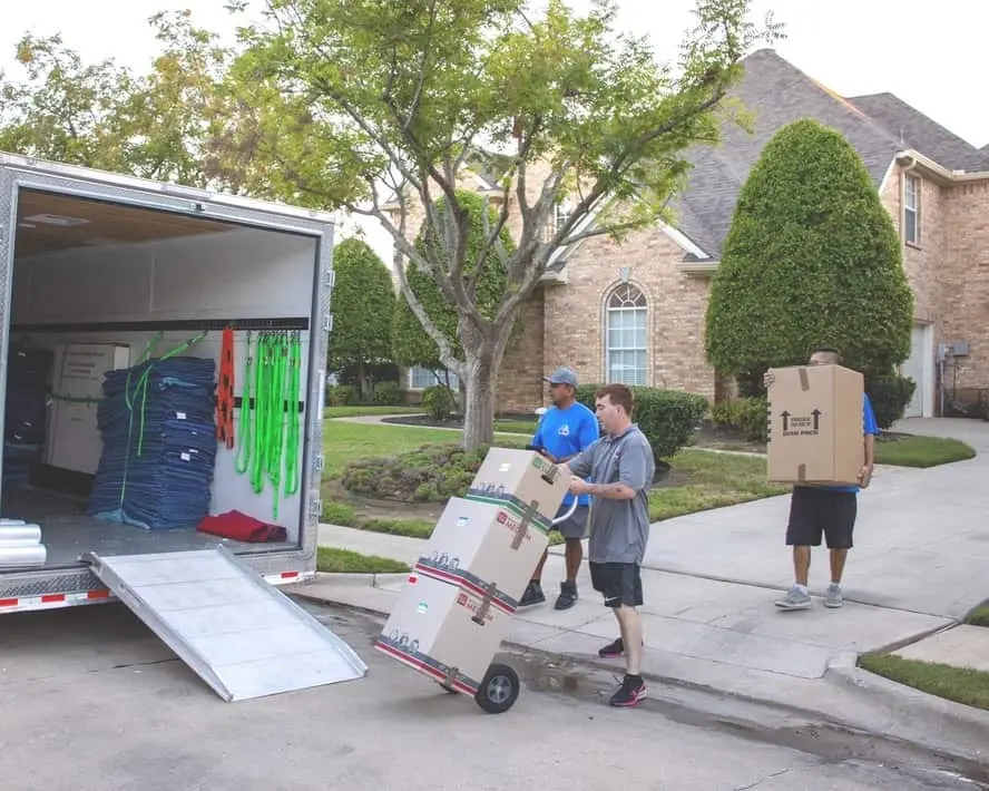 Texas Delta Moving team unloading boxes from a moving truck in front of a suburban home, showcasing professional and efficient moving services.