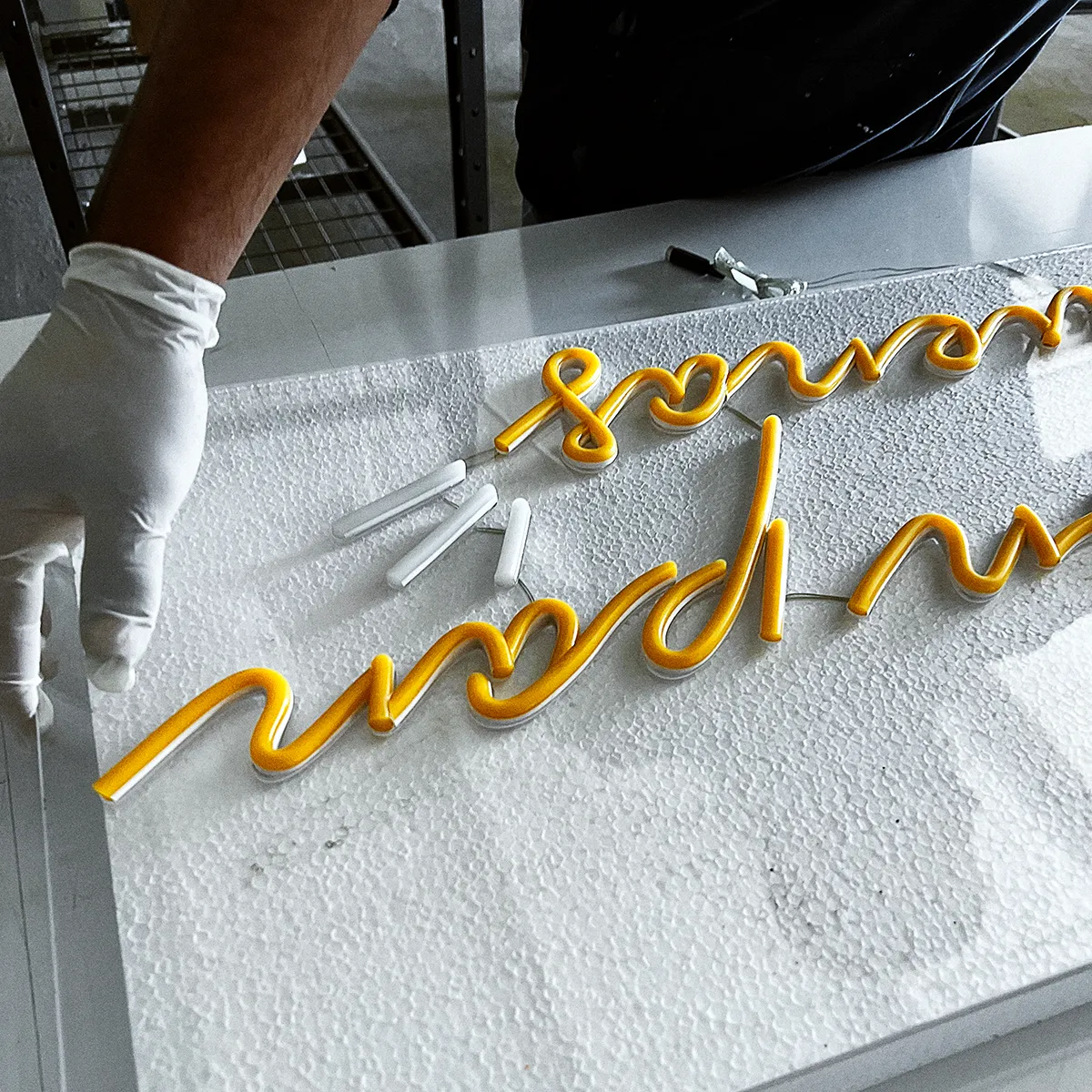 Fotografía de anuncio neón LED en proceso de fabricación color amarillo y blanco neutro