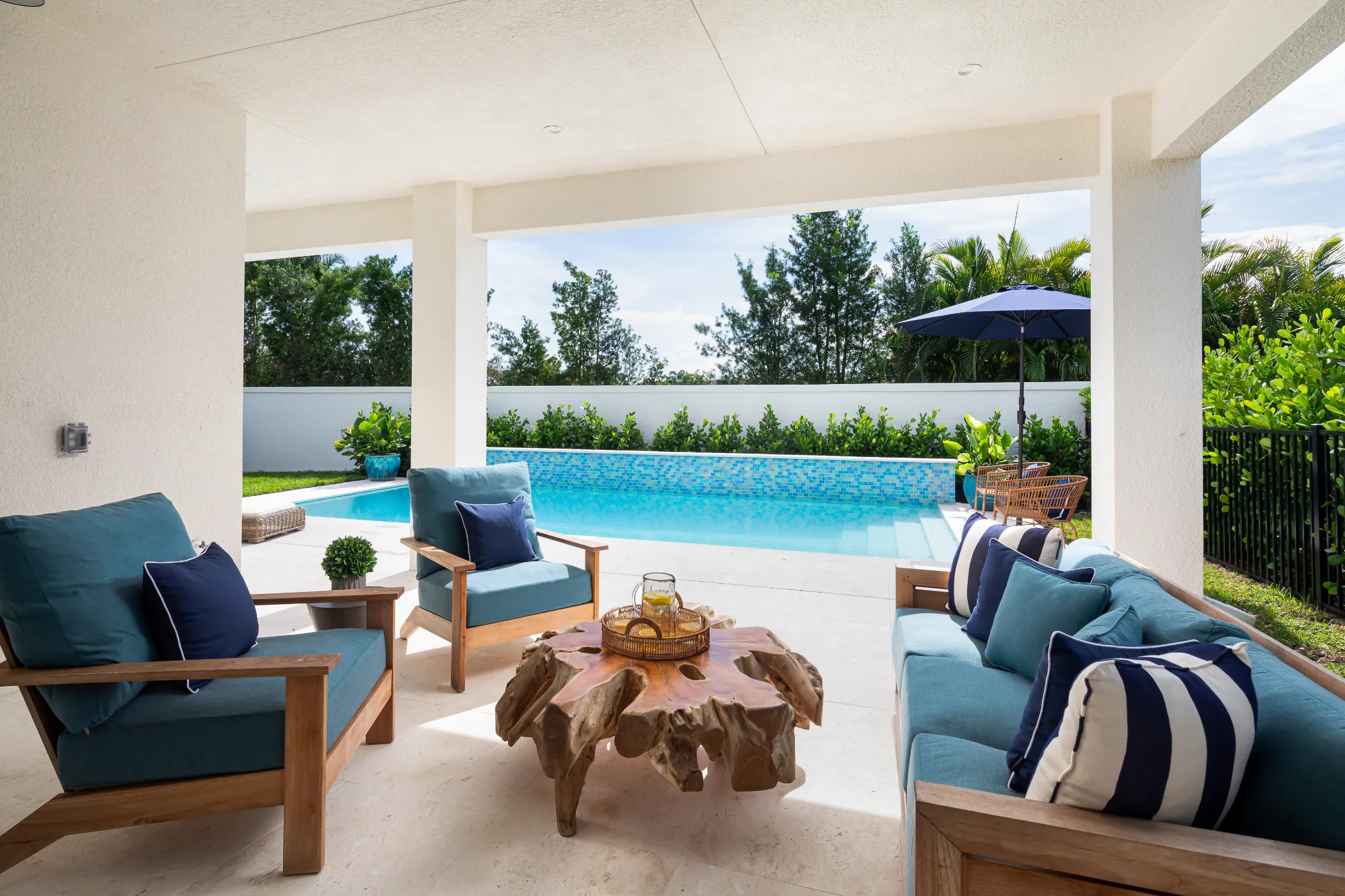 Outdoor patio with wooden furniture and a unique table overlooking a swimming pool.