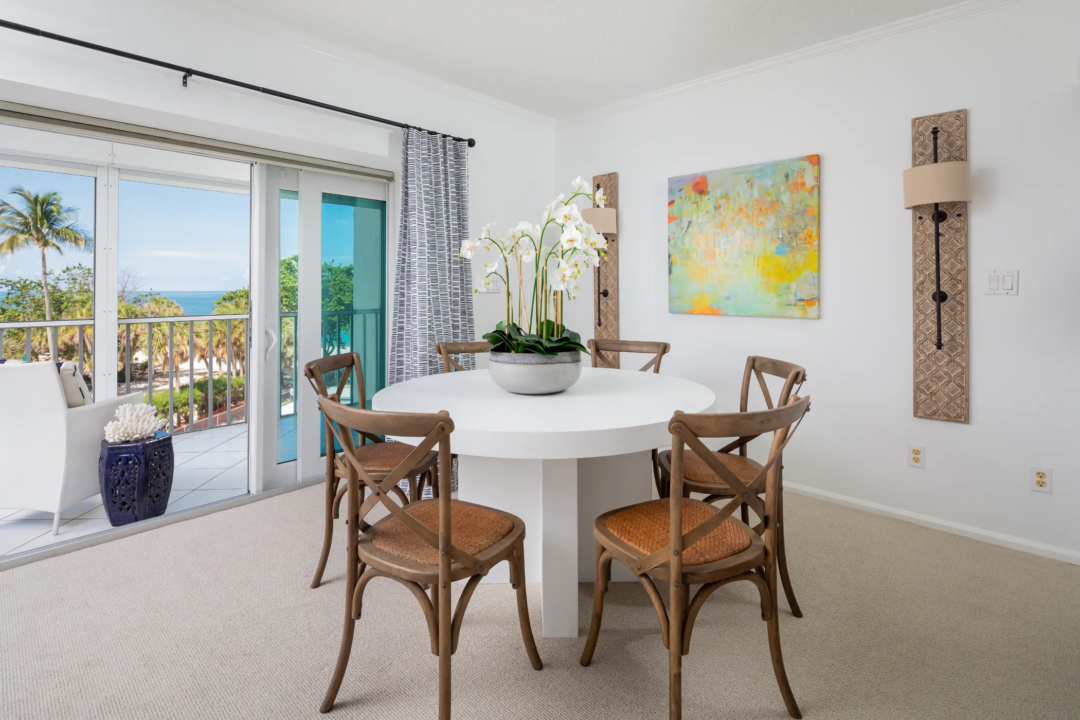 A dining room with a round table and chairs, featuring a potted plant in the center.