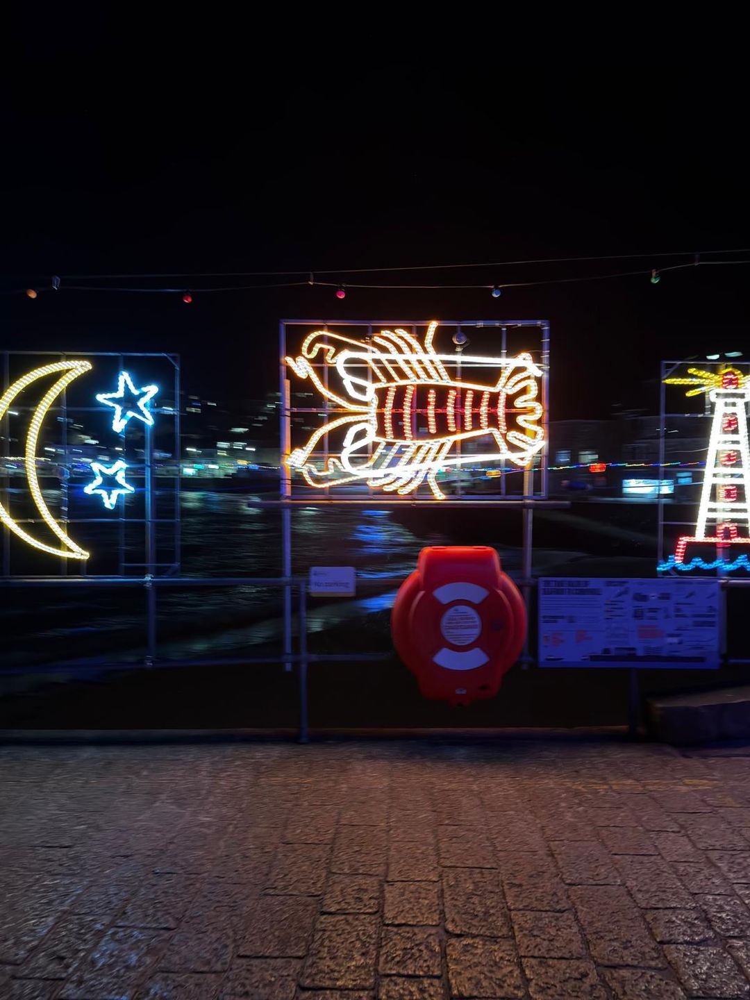 Illuminated moon, stars, lobster and lighthouse Christmas lights on the St Ives harbourside