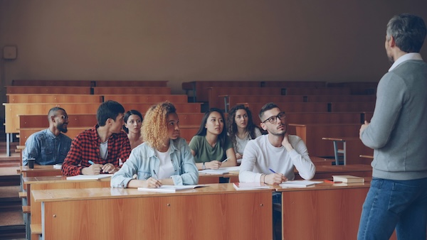 University students sitting in a lecture hall attentively listening to a class.