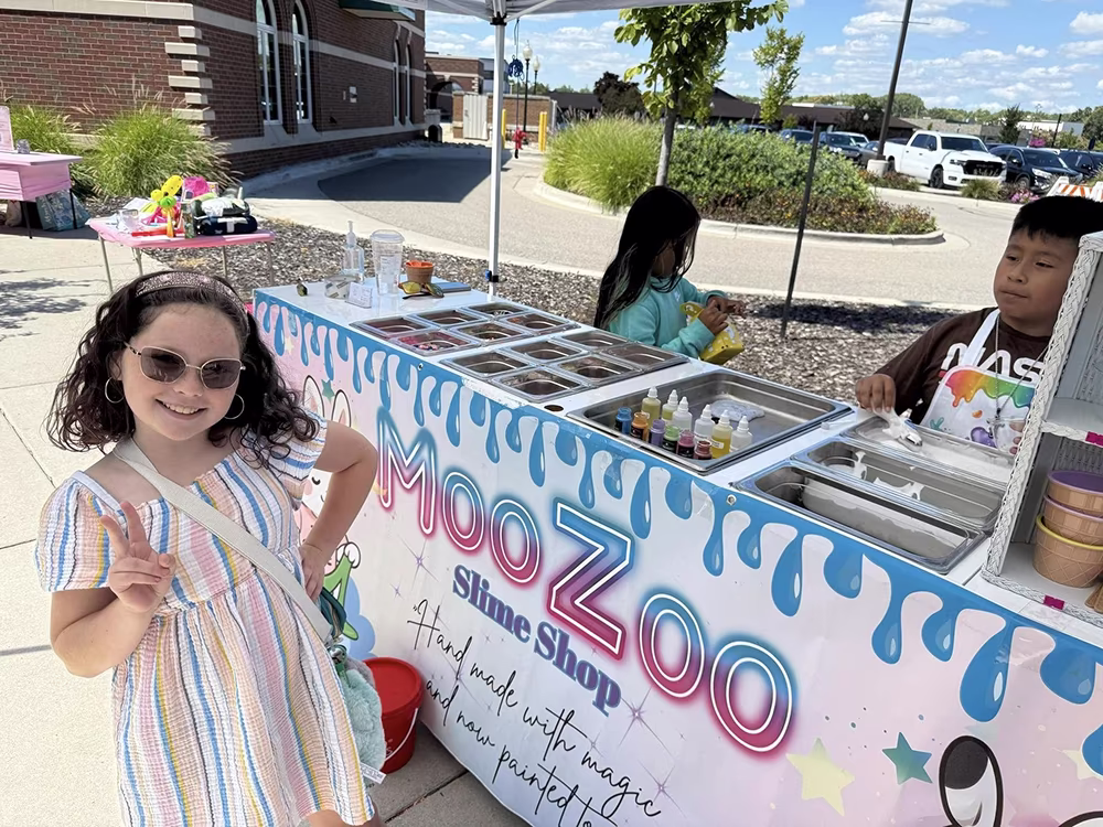 Girl standing in front of Moo Zoo Slime Shop's portable slime bar in Grand Rapids
