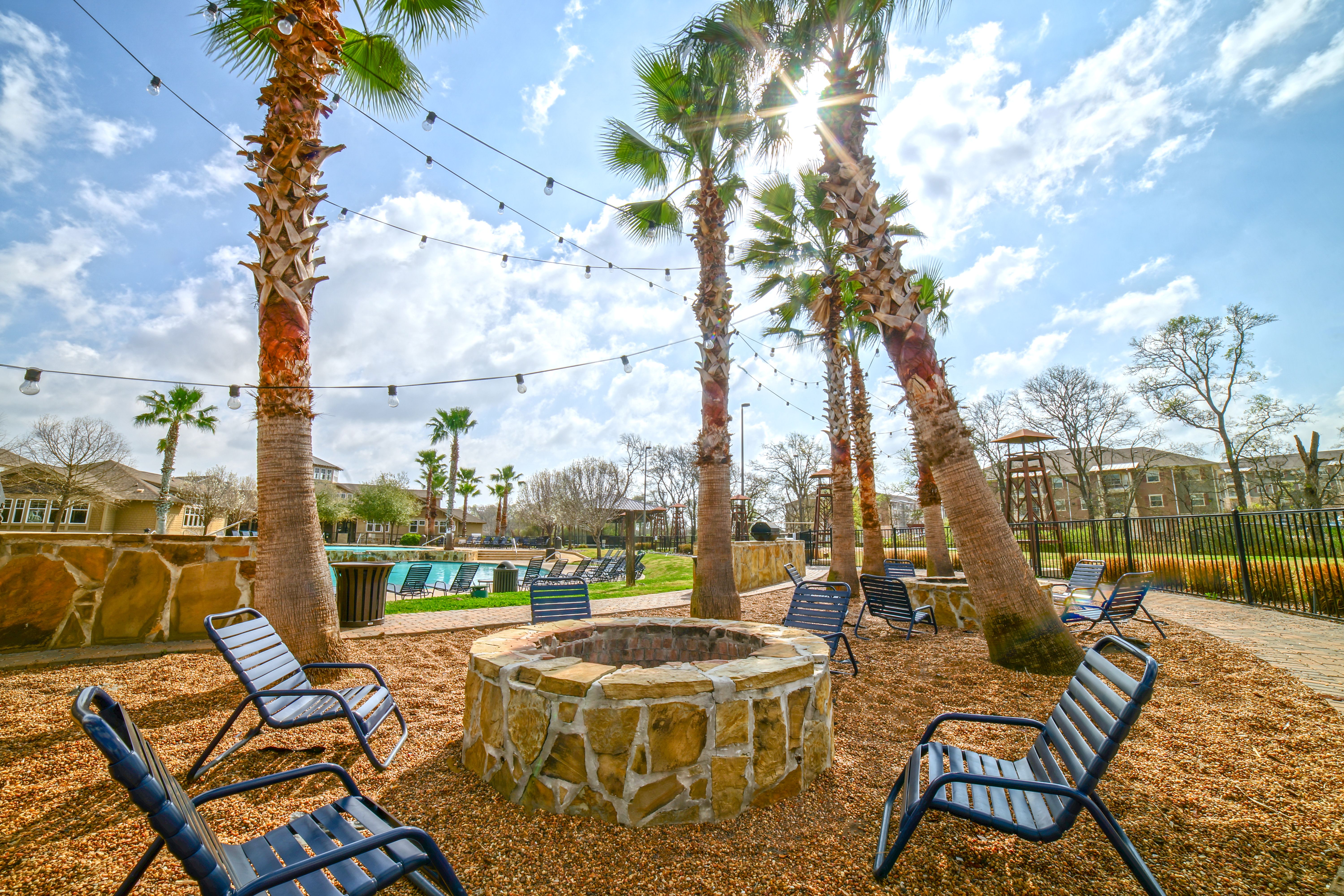 Firepit with chairs and swimming pool in background
