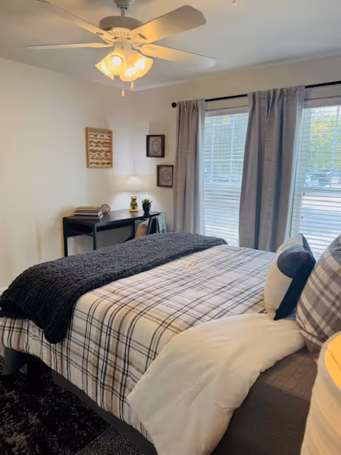 Bedroom with bed, desk, and large window