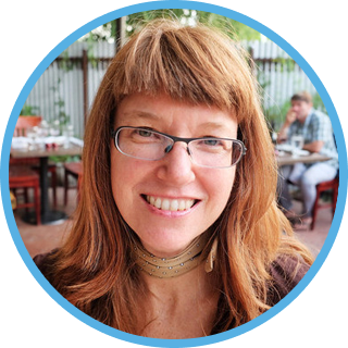 Shelli Winters' headshot. middle aged woman wearing glasses and smiling