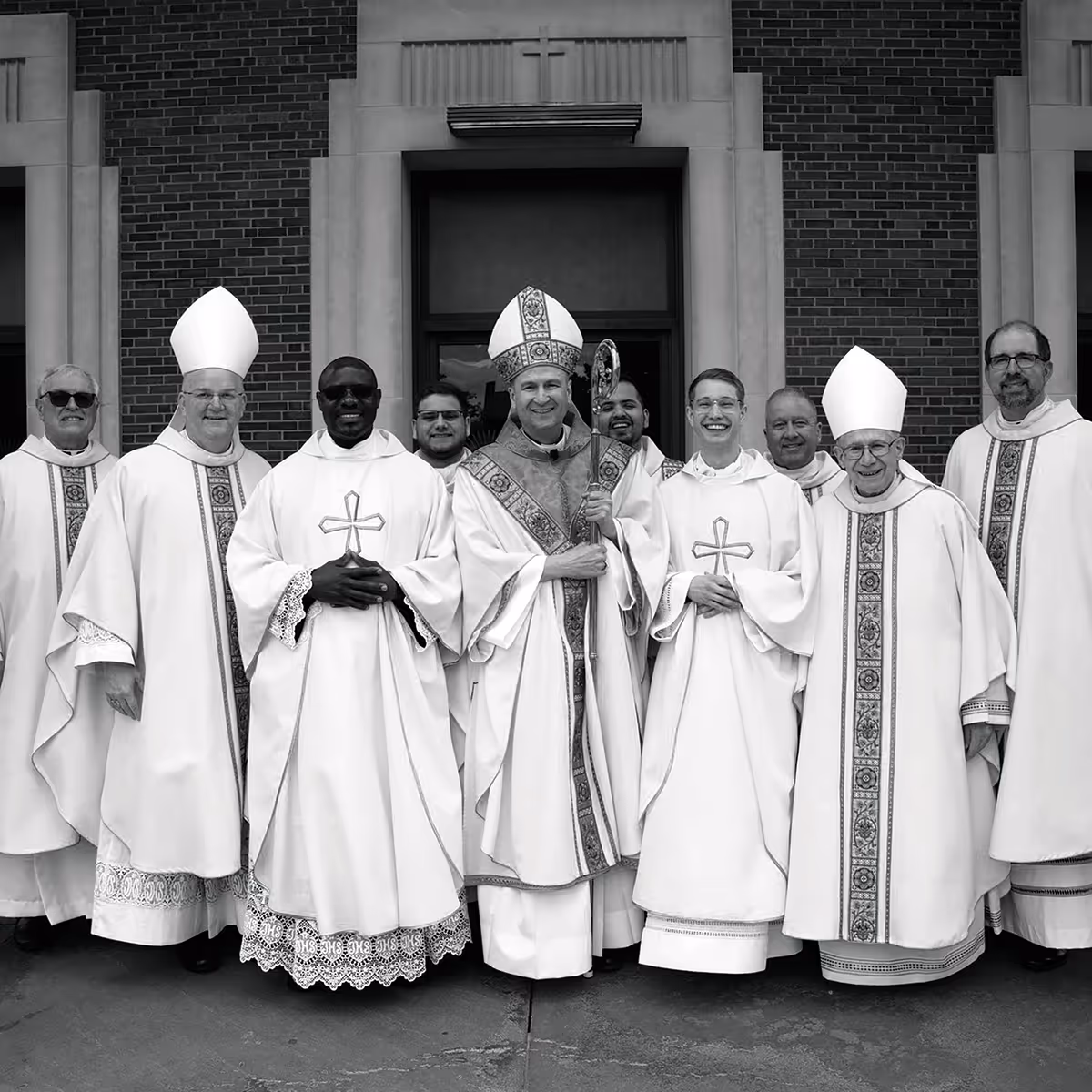 Bishop Hicks and priests group photo with play button icon