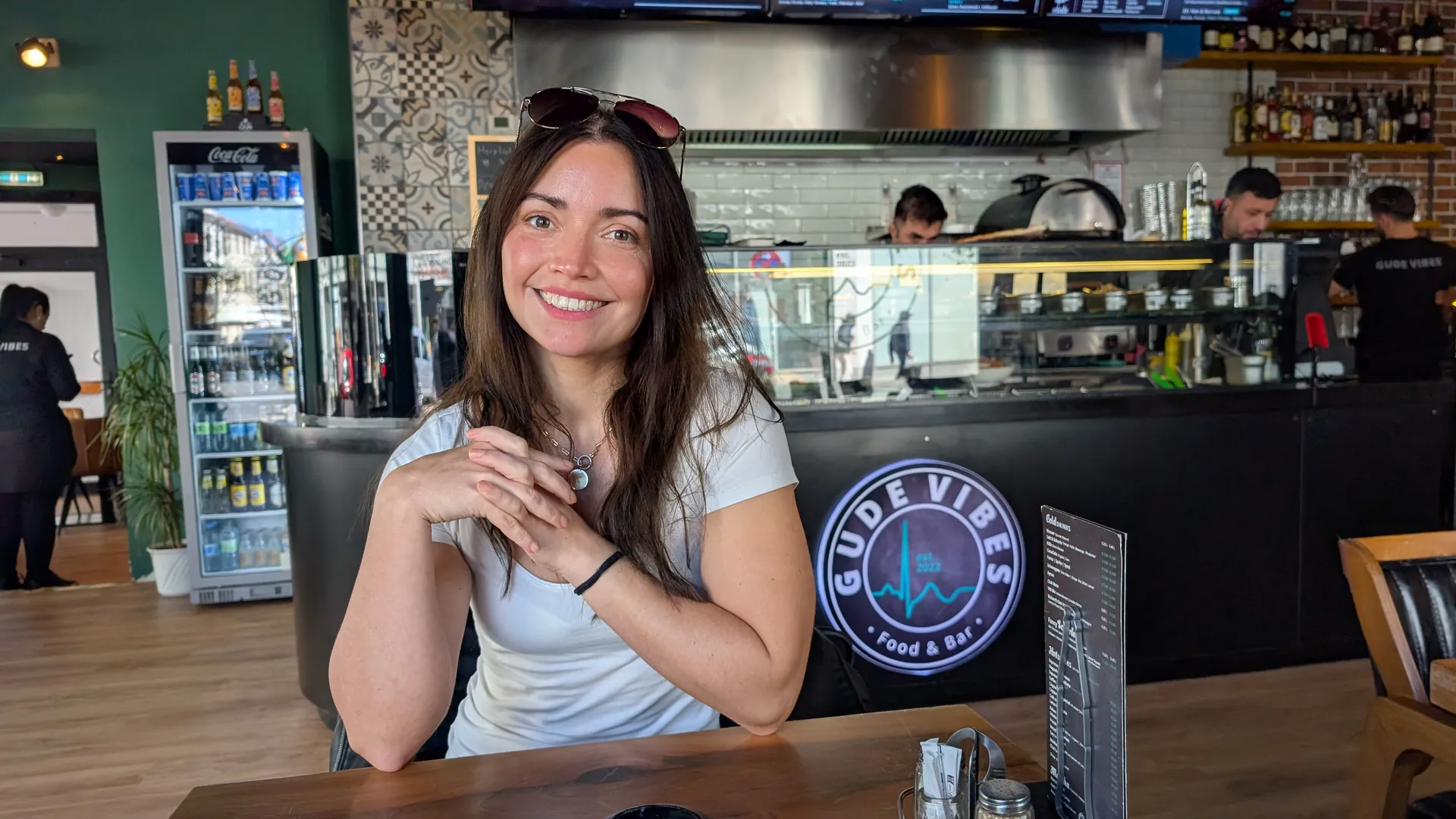 Magdalena am Tisch im Gude Vibes Uelzen, im Hintergrund die Theke mit dem Gude-Vibes-Logo