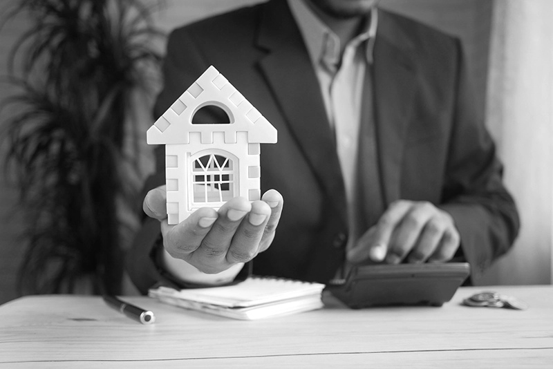 Photo of a man holding a little toy house in the palm of his hand