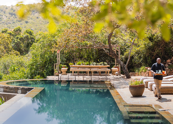 25-metre swimming pool surrounded by sunbeds and acacia trees.
