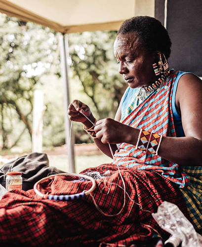 Maasai woman teaching beadwork to a guest.