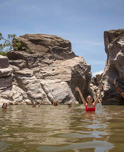 Guests swimming beneath a natural waterfall in the Mara.